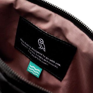 Bellroy Laneway Belt Bag interior showing fabric label with eco-friendly message on mauve lining