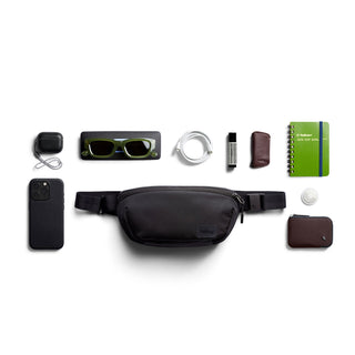 Bellroy Laneway Belt Bag in black nylon with everyday essentials laid out on white background