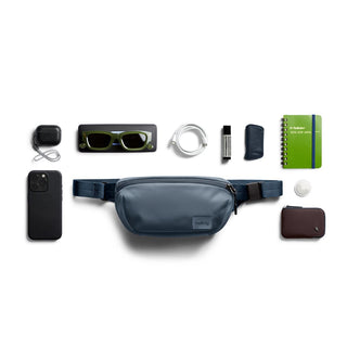 Bellroy Laneway Belt Bag in navy blue with smooth texture and organized everyday carry items around it