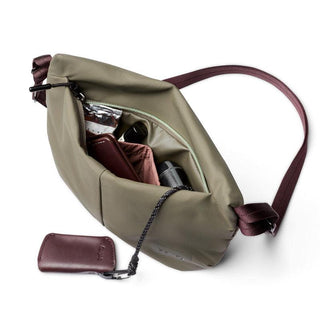 Bellroy Laneway Sacoche in olive green with maroon strap, open zipper showing organized interior compartments