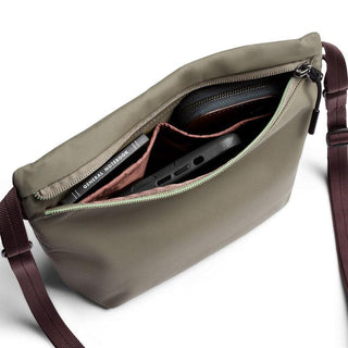 Bellroy Laneway Sacoche crossbody bag in olive green with multiple compartments open showing contents