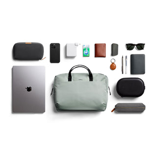Bellroy Via Work Bag (Tech Briefcase) in light grey with tech accessories and leather goods arranged neatly