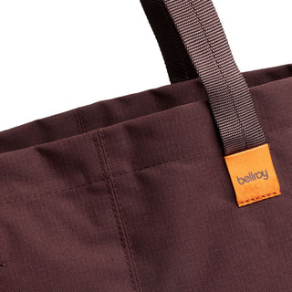 Bellroy Market Tote close-up showing deep brown recycled nylon fabric and orange logo tag on handle strap