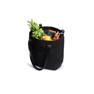 Bellroy Market Tote in black recycled nylon filled with groceries and fresh basil herb plant