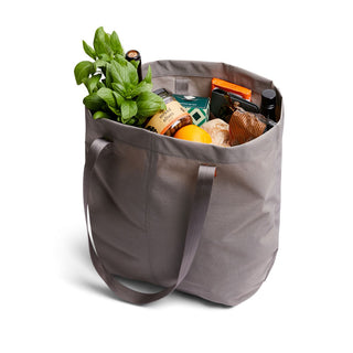 Bellroy Market Tote in gray nylon fabric filled with groceries including fresh herbs and packaged goods
