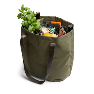 Bellroy Market Tote in olive green with sturdy handles filled with groceries and fresh herbs