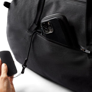 Bellroy Venture Duffel 55L in black showing front zip pocket storing smartphone and key fob