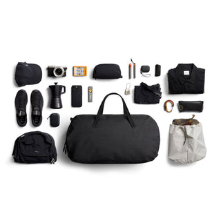 Bellroy Venture Duffel 55L black fabric travel bag surrounded by organized packed travel essentials