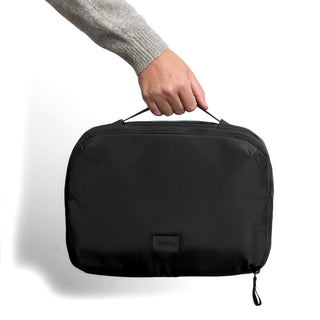 Bellroy Hanging Toiletry Kit Plus in black recycled fabric held by hand with top handle visible
