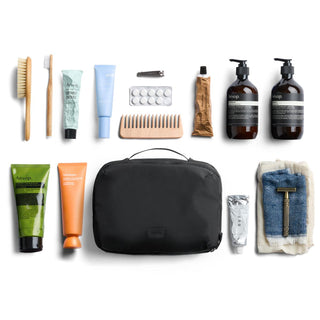 Bellroy Hanging Toiletry Kit Plus in black nylon fabric with personal care items neatly arranged around it