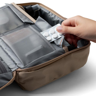 Bellroy Hanging Toiletry Kit Plus in tan with mesh compartments holding travel essentials and pills