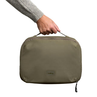 Bellroy Hanging Toiletry Kit Plus in olive green fabric held by top handle from side angle