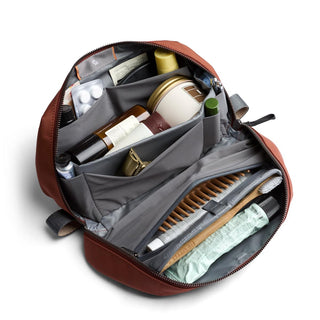 Bellroy Toiletry Kit Plus open showing organized compartments and travel essentials inside rust-colored fabric pouch