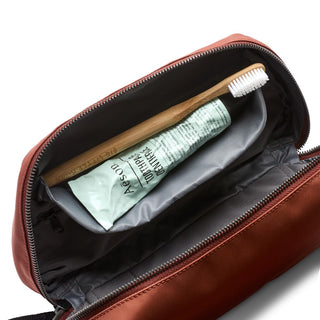 Bellroy Toiletry Kit Plus in brown with interior zipper pocket holding toothbrush and lotion tube