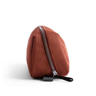 Bellroy Toiletry Kit Plus in rust fabric with silver zipper and black pull tab shown from side angle