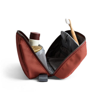 Bellroy Toiletry Kit Plus open with toiletry items inside, showcasing rust fabric and zipper detail