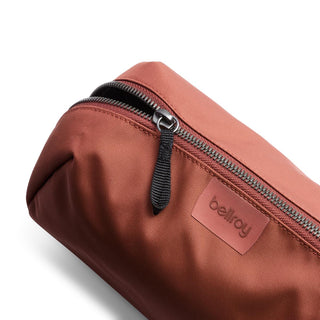 Bellroy Toiletry Kit Plus in rust fabric with black zipper and embossed logo tag detail