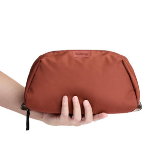 Bellroy Toiletry Kit Plus in rust color held by hand showing recycled fabric texture