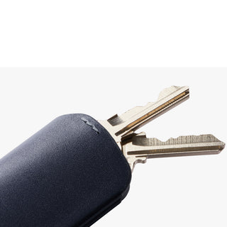 Bellroy Key Cover Third Edition in navy leather holding two metal keys with textured finish