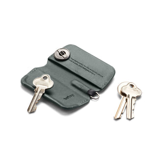 Bellroy Key Cover Third Edition in green leather with metal button and attached keys on white background