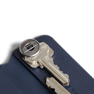 Bellroy Key Cover Plus Third Edition in navy leather holding two silver keys with metal lock mechanism