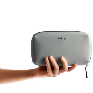 Bellroy Tech Kit in gray recycled fabric held from the side showing compact design and zipper closure