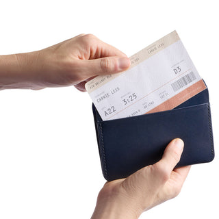 Bellroy Passport Cover in navy leather holding a boarding pass with clean stitching details