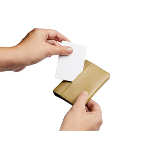 Hands inserting card into tan leather Bellroy Under Cover card holder with smooth texture