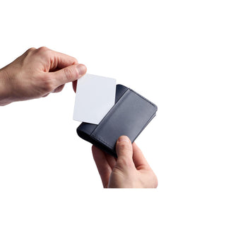 Bellroy Under Cover black leather card sleeve held with a hand inserting a card into the pocket