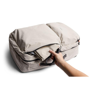 Bellroy Lite Travel Pack 38L beige backpack showing external pocket with packing cube being inserted by hand