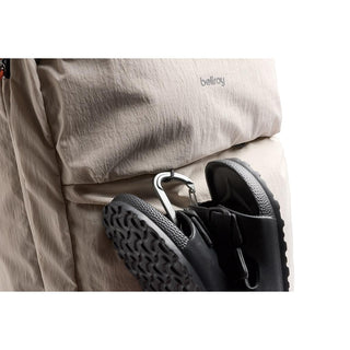 Bellroy Lite Travel Pack 38L in beige fabric with textured nylon and a clip holding black sandals