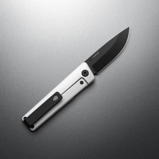 James The Chapter 2 Knife with black blade and titanium handle by The James Brand angled on gray surface