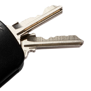 Bellroy Key Cover Third Edition showing textured black leather and two attached silver keys in close-up view