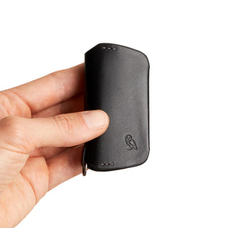 Bellroy Key Cover Third Edition held, showing smooth black leather texture with embossed owl logo detail