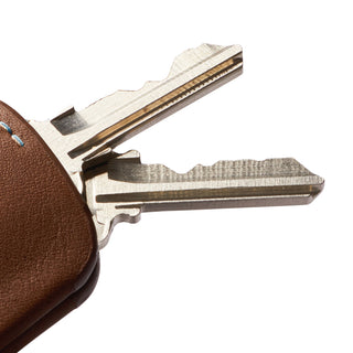 Bellroy Key Cover Third Edition in brown leather holding two silver keys with stitching detail