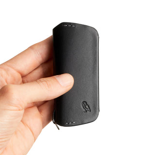 Hand holding Bellroy Key Cover Plus Third Edition in black leather with embossed owl logo