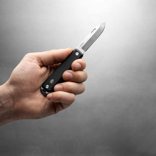 James The Ellis Slim Knife held in hand showing black G10 handle and stainless steel blade close-up
