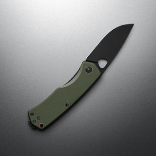 James The Folsom Knife with green G10 handle and black VG-10 blade by The James Brand angled on gray surface
