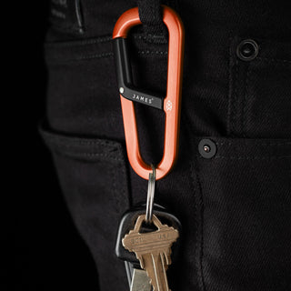James The Hardin Carabiner in anodized orange aluminum clipped to black pants holding keys
