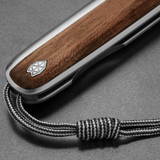 Close-up of James The Pike Knife handle with rosewood inlay and black-white braided lanyard by The James Brand