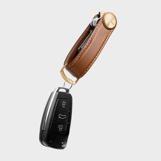 Orbitkey Key Organizer Pro Leather in brown holding several keys and a black car key fob on white background