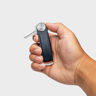 Orbitkey Key Organizer Pro Leather in navy held in hand with silver metal key attached