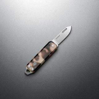 James The Elko Knife with eco-acetate handle and compact stainless steel blade angled on gray surface