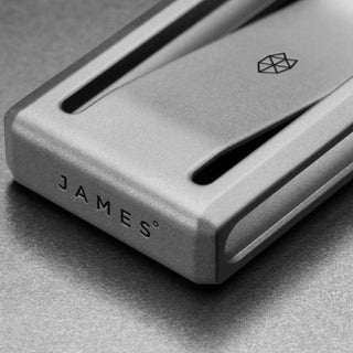 James The Martindale Money Clip in titanium showing close-up of smooth matte finish and engraved logo