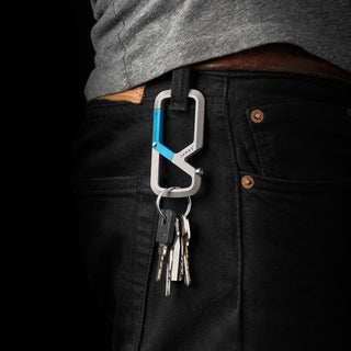James The Mehlville Carabiner in silver and blue aluminum clipped to black pants with keys attached