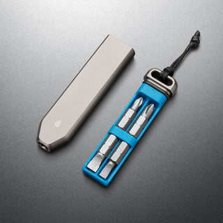 James The Warrick Bit Driver with anodized aluminum case and four steel screwdriver bits displayed on gray surface