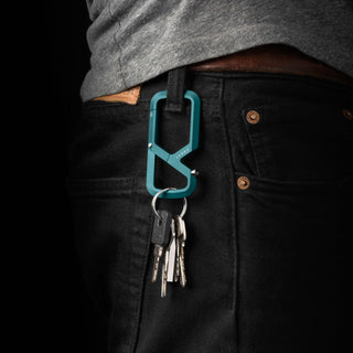 James The Mehlville Carabiner in teal anodized aluminum clipped to black jeans holding multiple keys