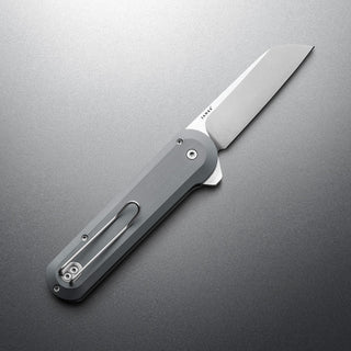 James The Wells Knife with sleek aerospace aluminum handle and sharp CPM Magnacut blade open on gray surface