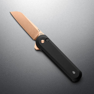 James The Wells Knife with black aluminum handle and copper-toned CPM Magnacut blade open on gray surface