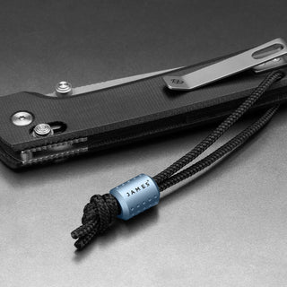 James The Alder Lanyard & Bead anodized aluminum bead on black nylon paracord attached to folding knife